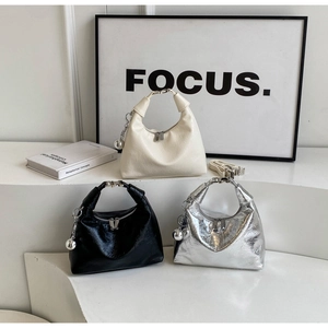 Three half-moon handbags in cream, black, and silver with stylish pleated texture and charms