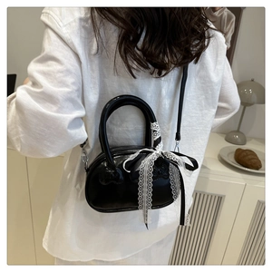 Detail of black patent leather bag with lace bow and hello kitty embossed pattern