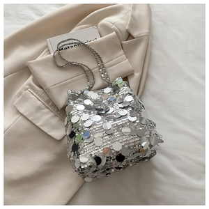Detail of silver sequin bucket bag featuring metallic chain strap on soft fabric