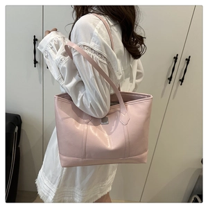 Detailaufnahme der rosa Tragetasche mit Markenprägung und eleganter Metall-Logoplatte
