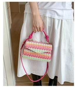 Detail of colorful woven handbag with pink leather handle and stylish knot decoration