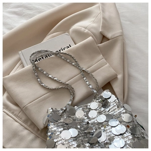 Close-up of bright silver sequins and woven chain strap on a stylish bucket bag