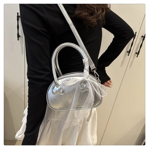 Silver metallic crossbody bag with lace bow accessory shown worn by a model