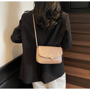Chic beige underarm bag with gold U-shaped metal buckle styled on a modern interior staircase