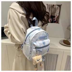 Close-up of mini backpack with blue butterfly print and yellow plush monster charm