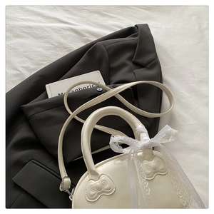 Detail of cream white leather handbag with lace bow and stylish texture engraving