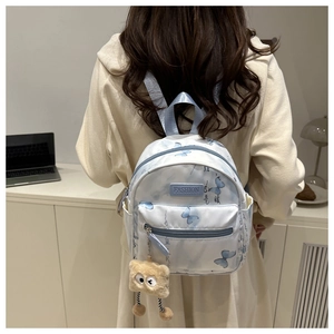 Detailansicht eines blauen Mini-Schmetterlings-Rucksacks mit Kalligraphie und Anhänger