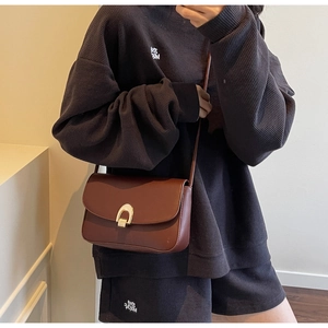 Detail of vintage brown leather bag featuring a polished gold U-shaped metal buckle