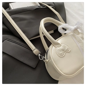 Detail of cream white PU leather handbag with bow patch and elegant lace ribbon handle