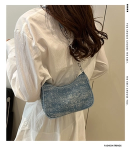 Sac sous le bras en denim bleu avec strass et chaîne argentée sur chemise blanche