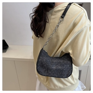 Détail du sac demi-lune en tweed gris foncé avec chaîne argentée porté par le mannequin
