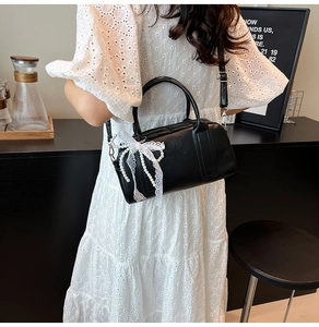 Détail du sac Boston noir mat avec charme de nœud en dentelle blanche et perles