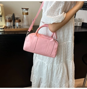 Close-up of pink Boston bag showing embossed text detail and premium leather texture