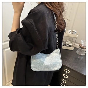 Détail du sac à bandoulière bleu scintillant avec chaîne argentée sur un modèle