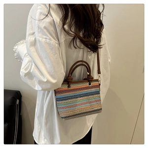 Sac en paille à rayures arc-en-ciel avec poignées en cuir sur une chemise blanche