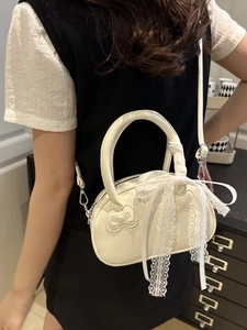White semi-circular handbag with 3D bow detail and elegant lace ribbon on black backdrop
