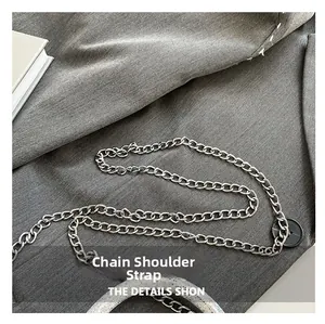 Macro detail of silver metal chain shoulder strap and black buckle on a textured bag