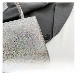 Detail of silver sequin evening bag fabric showing glitter texture and metallic handle