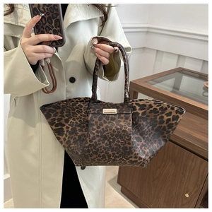Detailed close-up of a leopard print tote bag with a golden metal plate and long handles