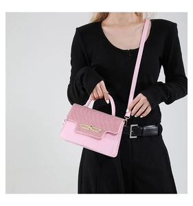 Pink faux leather crossbody bag with woven texture flap and gold lock shown on model