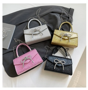 Detail view of four glittery bow bags in silver, gold, pink and black with chain straps