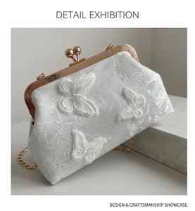Detail shot of white lace shell bag with 3D butterfly embroidery and gold metal clasp