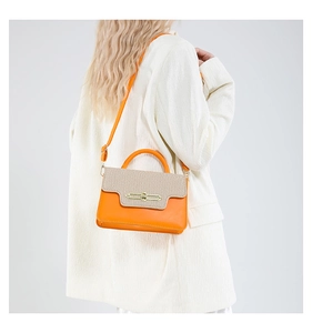 Detail view of orange leather and woven crossbody bag with gold lock on white blazer
