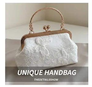 Detail of white lace handbag with vintage golden metal handle and clasp closure