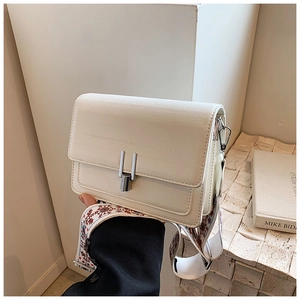 Close-up of a white rectangular bag featuring a silver buckle and jacquard shoulder strap