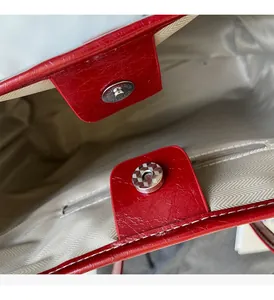Detail of red textured faux leather tote bag interior with magnetic closure and zipper pocket