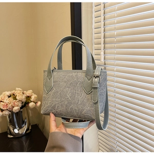 Détail du sac à main en tissu texturé bleu-gris avec finitions argentées et cuir