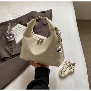 Detail of off-white dumpling bag showing gathered texture, silver zippers and metal charm