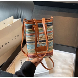 Detail of colorful striped straw handbag with leather handles and fashion label