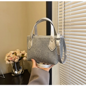 Détails du tissu gris marbré et des poignées métalliques argentées d'un mini sac cabas