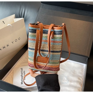 Detail of colorful striped woven mini bag with brown leather trim in a gift box setup