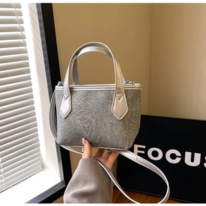 Détail du sac seau gris texture denim avec poignées en PU argenté et bandoulière