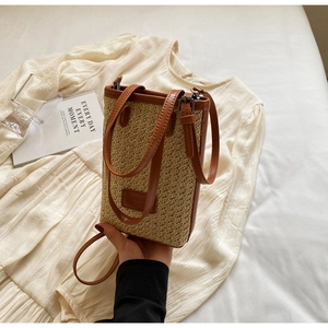 Détail du sac cabas tissé en paille avec poignées en cuir marron et bandoulière réglable