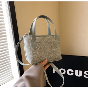 Gros plan du sac seau en toile texturée bleu clair avec poignée en cuir et zip