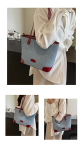 Detail of large denim tote bag with red leather trim for stylish office commuting