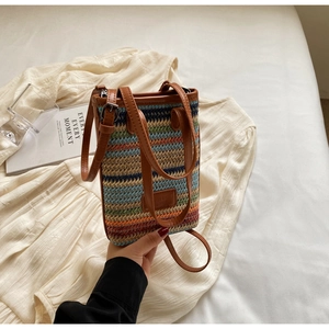 Vue de dessus d'un petit sac en paille tissé coloré avec lanières en cuir brun et métal