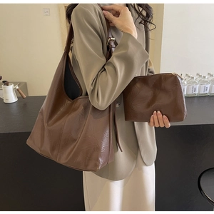 Detail of dark brown vintage tote bag and matching pouch with wrinkled leather texture