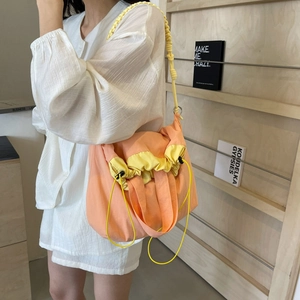 Borsa a tracolla in nylon rosa e giallo con tracolla intrecciata su una modella donna