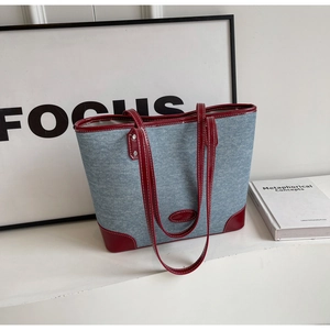 Detail of blue denim tote bag with red leather trim and white contrast stitching