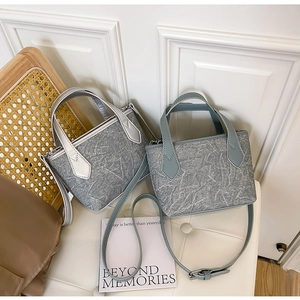 Détail de sacs seaux en denim tendance gris et bleu avec lanières en similicuir