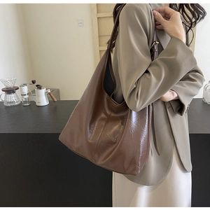 Detail of dark brown hobo bag with pleated texture and stylish slouchy shoulder strap