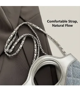 Détail de la bandoulière chaîne argentée et patchwork de denim bleu sur le sac à main
