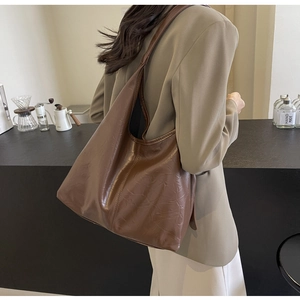 Retro large brown tote bag in wrinkled faux leather shown on shoulder in a cafe setting