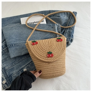 Dettaglio borsa a tracolla in paglia intrecciata con ciliegie ricamate su denim bianco