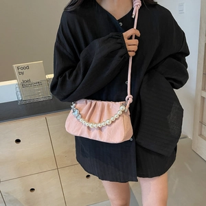 Pink pleated dumpling bag with pearl chain and heart charms on a black shirt model