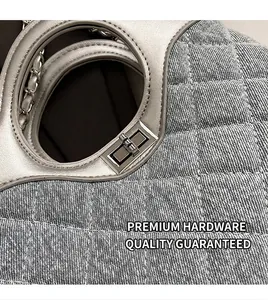 Détail d'un sac à main en jean matelassé bleu avec poignée ronde argentée et fermoir rotatif